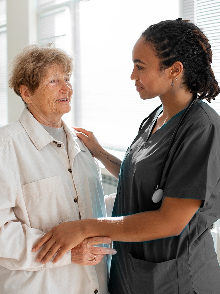 Nurse comforting elderly woman at home during palliative care visit